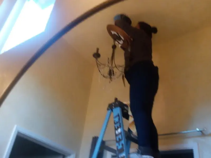 Electrician installing a chandelier in a McMinnville residence
